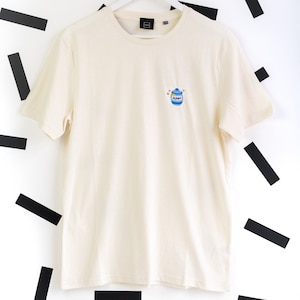 以下が含まれることがあります： クリーム色のTシャツに、青と白の刺繍で「マスタード」と書かれた瓶が描かれています。