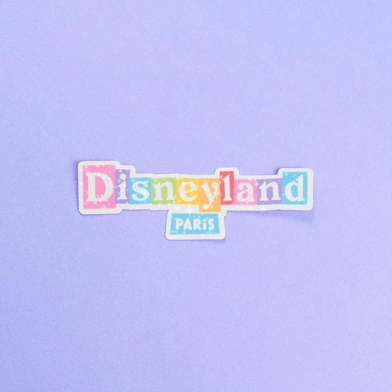 May include: A colorful sticker with the text "Disneyland Paris" in white letters on a rainbow background.