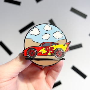 May include: Red and yellow cartoon race car with the number 95 on the side. The car is on a brown background with blue clouds.