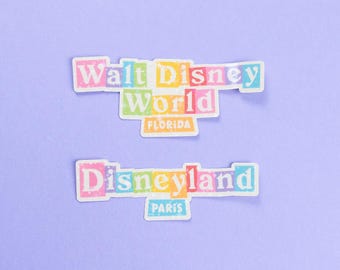 May include: Two colorful stickers with the text "Walt Disney World Florida" and "Disneyland Paris" on a light purple background.