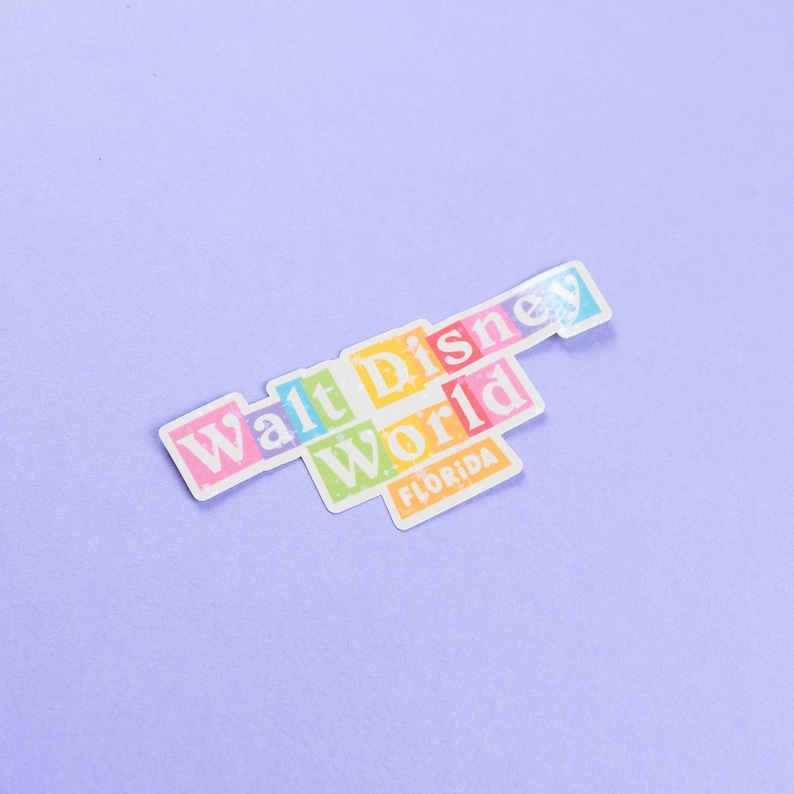 May include: A colorful sticker with the text "Walt Disney World" and "Florida" in white letters. The sticker is on a light purple background.