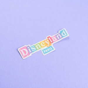 May include: A colorful sticker with the text "Disneyland Paris" in a blocky font.