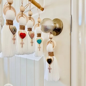 May include: A set of six white tassel door hangers with wooden rings, hearts, and crosses. Each heart features a different colored gemstone.