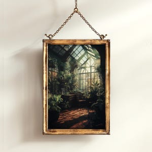 May include: A framed print of a sunlit greenhouse interior, filled with lush greenery and architectural details. The gold-toned frame is suspended by a delicate chain. The artwork depicts a serene indoor garden scene.