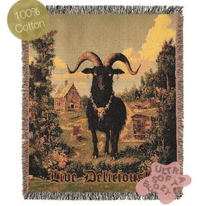 May include: A woven tapestry throw blanket featuring a black goat with horns and a skull necklace standing in a field with a farmhouse in the background. The text "Live Deliciously" is printed at the bottom of the blanket.