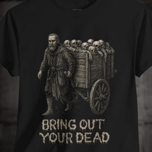 Peut inclure: T-shirt noir avec une illustration détaillée en noir et blanc d'un homme tirant une charrette remplie de crânes. Le texte "BRING OUT YOUR DEAD" est imprimé en dessous, dans une police vieillie, pour un style gothique vintage.