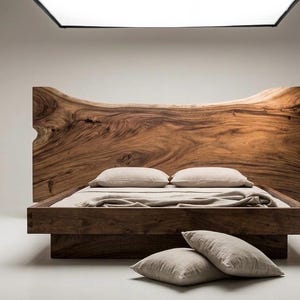 Könnte beinhalten: Ein modernes Holzbett mit einem großen Kopfteil mit natürlicher Kante. Das Bett hat ein niedriges Profil und ist aus dunklem Holz gefertigt. Zwei Kissen liegen auf dem Bett, zwei weitere Kissen auf dem Boden. Die Bettwäsche ist neutral gefärbt.