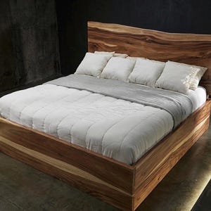 May include: A wooden bed frame with a natural wood headboard. The bed is made with a light-colored wood and features a white comforter and pillows. The bed frame is approximately 78 inches long and 60 inches wide.