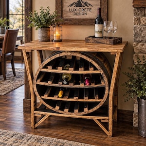 May include: A rustic wooden wine rack console table featuring a repurposed barrel base with horizontal shelving for wine bottles. The top surface holds a bottle of red wine, two clear glass wine glasses on a wooden tray, and a potted green plant.