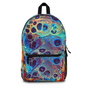 Puede incluir: Una mochila colorida con un diseño abstracto vibrante en tonos de azul, naranja y morado. La mochila tiene un asa negra, un bolsillo frontal con cremallera y un bolsillo lateral de malla. El patrón se asemeja a un efecto fluido y veteado.