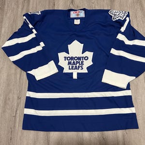 May include: A set of three ceramic mugs with a speckled, matte finish. The mugs are in cream, light grey, and dark grey. Each mug has a simple, minimalist design, ideal for coffee or tea.