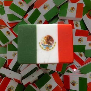 May include: Rectangular flag-shaped charms with the Mexican flag design. The charms feature green, white, and red stripes, with the Mexican coat of arms in the center. The charms are scattered across a surface.