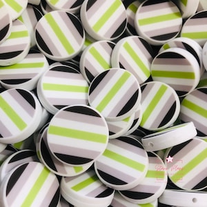 May include: A collection of round, white buttons with a striped design in black, gray, and lime green. The buttons are stacked together, creating a visually appealing pattern. The buttons have a glossy finish.