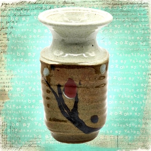 May include: A small, brown and white ceramic vase with a wide mouth and a narrow neck. The vase has a hand-painted design of a brown branch with a red flower and white dots.