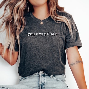 May include: A dark grey heather t-shirt with the text "you are p<0.05" printed in white.