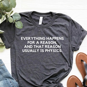 Peut inclure: Un t-shirt gris foncé chiné avec le texte "Everything happens for a reason, and that reason usually is physics." imprimé en blanc.