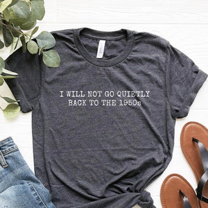 May include: A dark gray t-shirt with the text "I WILL NOT GO QUIETLY BACK TO THE 1950s" printed in white.
