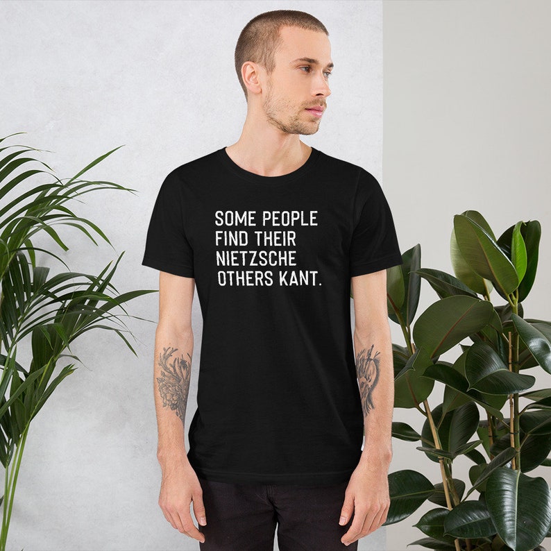 May include: Black t-shirt with white text that reads "Some people find their Nietzsche others Kant."
