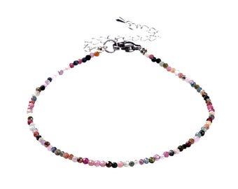 May include: A delicate bracelet made of small, colourful beads. The beads are a mix of pink, blue, green, and black. The bracelet has a silver clasp.