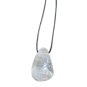Puede incluir: Un colgante de cristal de cuarzo transparente en un collar de cordón negro. El cristal es liso y tiene forma de lágrima.