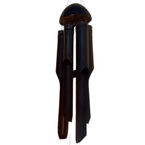 May include: A black bamboo wind chime with a round, dark brown top. The chime has five tubes of varying lengths.