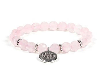 May include: A pink rose quartz beaded bracelet with a silver lotus flower charm. The bracelet is made with round beads and has a simple design.