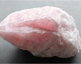 May include: A large, rough, pink rose quartz crystal with white veins. The crystal is opaque and has a smooth, polished surface.