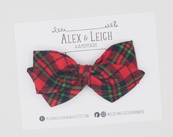 May include: Red and green plaid bow tie with black accents. The bow tie is handmade and is on a white card with the text "Alex & Leich Handmade".