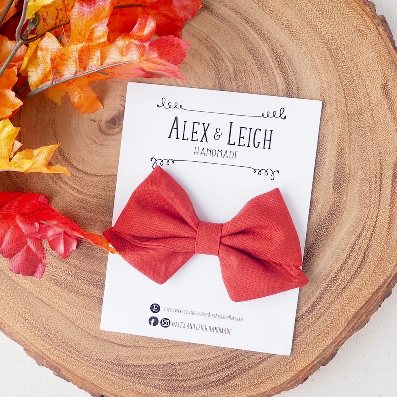 Pu&ograve; includere: Un papillon in tessuto color ruggine su una carta bianca con il testo "Alex & Leigh Handmade".