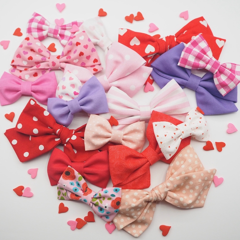 Peut inclure: Un assortiment de n&oelig;uds pour cheveux en tissu faits &agrave; la main dans diff&eacute;rentes couleurs et motifs, notamment des pois rouges, blancs, roses, bleus et noirs. Les n&oelig;uds sont fabriqu&eacute;s avec diff&eacute;rents tissus, tels que le coton et le satin, et sont nou&eacute;s avec un ruban.