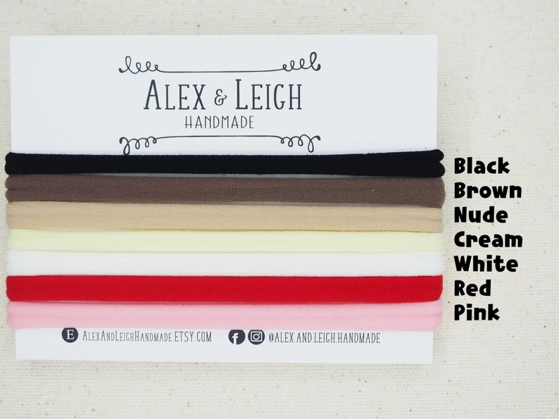 Puede incluir: Un conjunto de ocho cintas para el pelo en varios colores, incluyendo negro, marr&oacute;n, nude, crema, blanco, rojo y rosa. Las cintas para el pelo est&aacute;n dispuestas en una pila, con los colores visibles. El texto "ALEX & LEIGH HANDMADE" est&aacute; impreso en una tarjeta blanca detr&aacute;s de las cintas para el pelo.