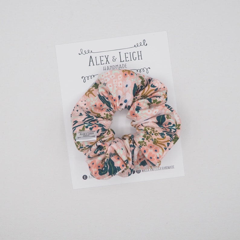 K&ouml;nnte beinhalten: Ein rosa-gr&uuml;ner Scrunchie mit floralem Muster und einem wei&szlig;en Gummiband. Der Scrunchie ist handgefertigt von Alex & Leigh.