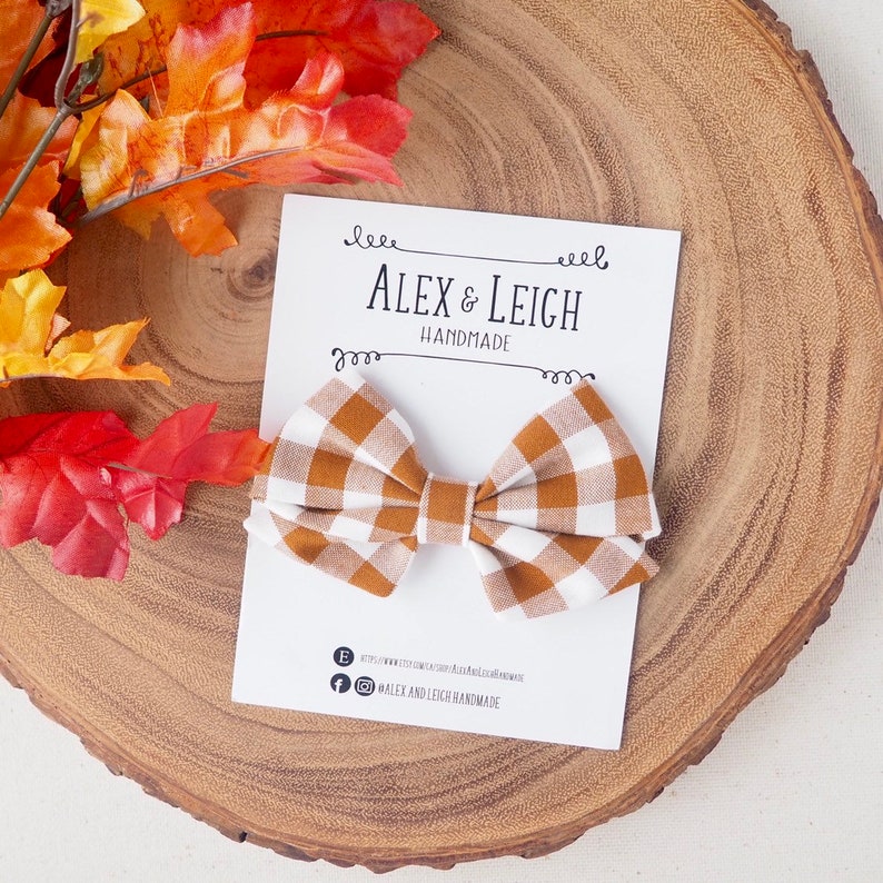 Pu&ograve; includere: Un fiocco gingham marrone e bianco con un biglietto bianco che dice "Alex & Leigh Handmade".