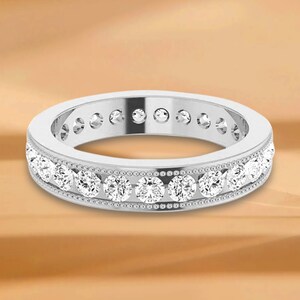 Könnte beinhalten: Ein silberner Ring mit einer Reihe runder Diamanten, die in einem Milgrain-Design gefasst sind.