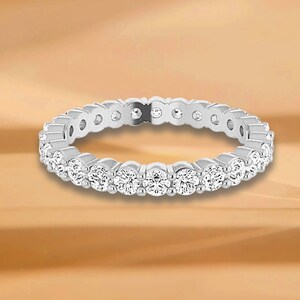 Könnte beinhalten: Ein silberner Ewigkeitsring mit einer Reihe kleiner, runder, klarer Diamanten.