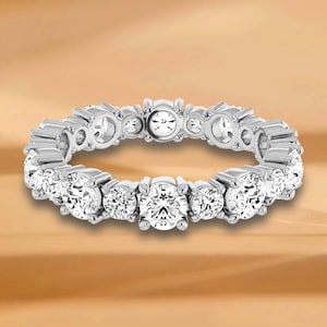 Könnte beinhalten: Ein silberner Ewigkeitsring mit einer Reihe runder, klarer Diamanten.