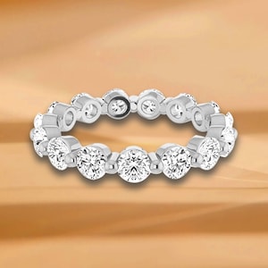 Könnte beinhalten: Ein silberner Bandring mit einer Reihe runder, klarer Diamanten.