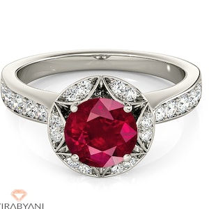 May include: A silver ring featuring a large red ruby gemstone encircled by a halo of smaller diamonds. The band is also set with smaller diamonds.