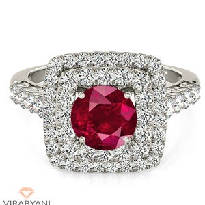 May include: A silver ring with a large red ruby surrounded by two rows of smaller diamonds. The ring has a square shape and a twisted band.