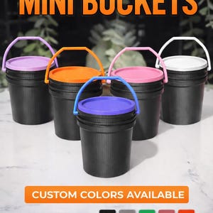 May include: A selection of black mini buckets with lids and handles in various colours. The lids and handles are in purple, orange, pink, and white. The text "MINI BUCKETS" is at the top, with "CUSTOM COLORS AVAILABLE" below.