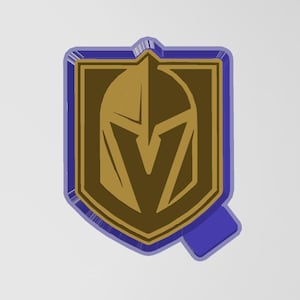 Puede incluir: Un emblema dorado y marrón en forma de escudo con un borde azul. El emblema presenta un casco de caballero estilizado y la letra "V". El diseño está sobre un fondo blanco.