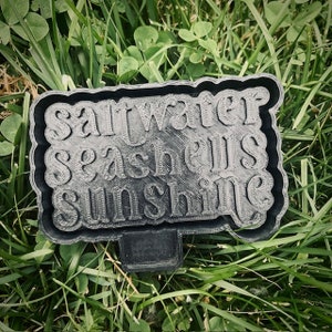 May include: Black plastic sign with the words "saltwater seashells sunshine" in white lettering.