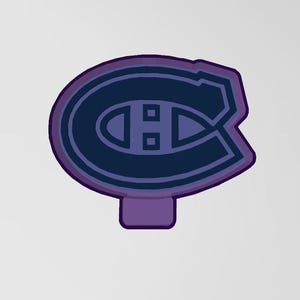 Könnte beinhalten: Ein lila-blaues Logo der Eishockeymannschaft Montreal Canadiens. Das Logo zeigt ein stilisiertes "C" mit einem "H" darin und einen lila Umriss. Das Logo befindet sich auf einem hellgrauen Hintergrund.
