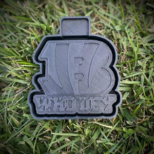 May include: Black 3D printed keychain with the text "WHO DEY" and a football design.