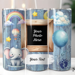 May include: A blue tumbler with a baby theme. The design includes a rainbow, hot air balloon, stars, a cute elephant, a frame with the text "Your Photo Here", a balloon, baby footprints, and the text "Your Text".