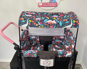 May include: A black and gray wagon with a pink handle and a canopy featuring a colorful dinosaur pattern. The wagon has two seats and a storage compartment. The text "Crafted by Chi" is visible on a sign above the wagon.