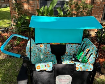 May include: A black and teal wagon with a teal canopy. The wagon has two seats with a teal animal print. The wagon has a black frame and teal handle. The wagon has a label that says "Crafted by Chi".