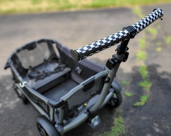 May include: A grey utility wagon with a black and white chequered handle. The wagon has a black interior and mesh sides. The wheels are black, and the frame is grey. Designed for outdoor use.