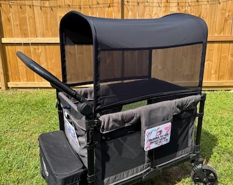 May include: A black and gray utility wagon with a canopy, designed for outdoor use. The wagon features a black frame, large wheels, and a storage compartment. The canopy is made of a mesh material. The wagon is on a grassy surface.