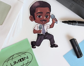 May include: A sticker depicting a cartoon man in a white shirt, blue striped tie, and dark trousers, holding two microphones. The sticker is on a white surface with a green notepad and a black pen.
